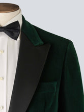 Load image into Gallery viewer, A green velvet dinner jacket designed for black-tie events, featuring a single-breasted one-button closure with a link button, silk peak lapels, and elegant paisley lining. Styled with a classic white dinner shirt and black silk bow tie adding timeless sophistication to the ensemble.