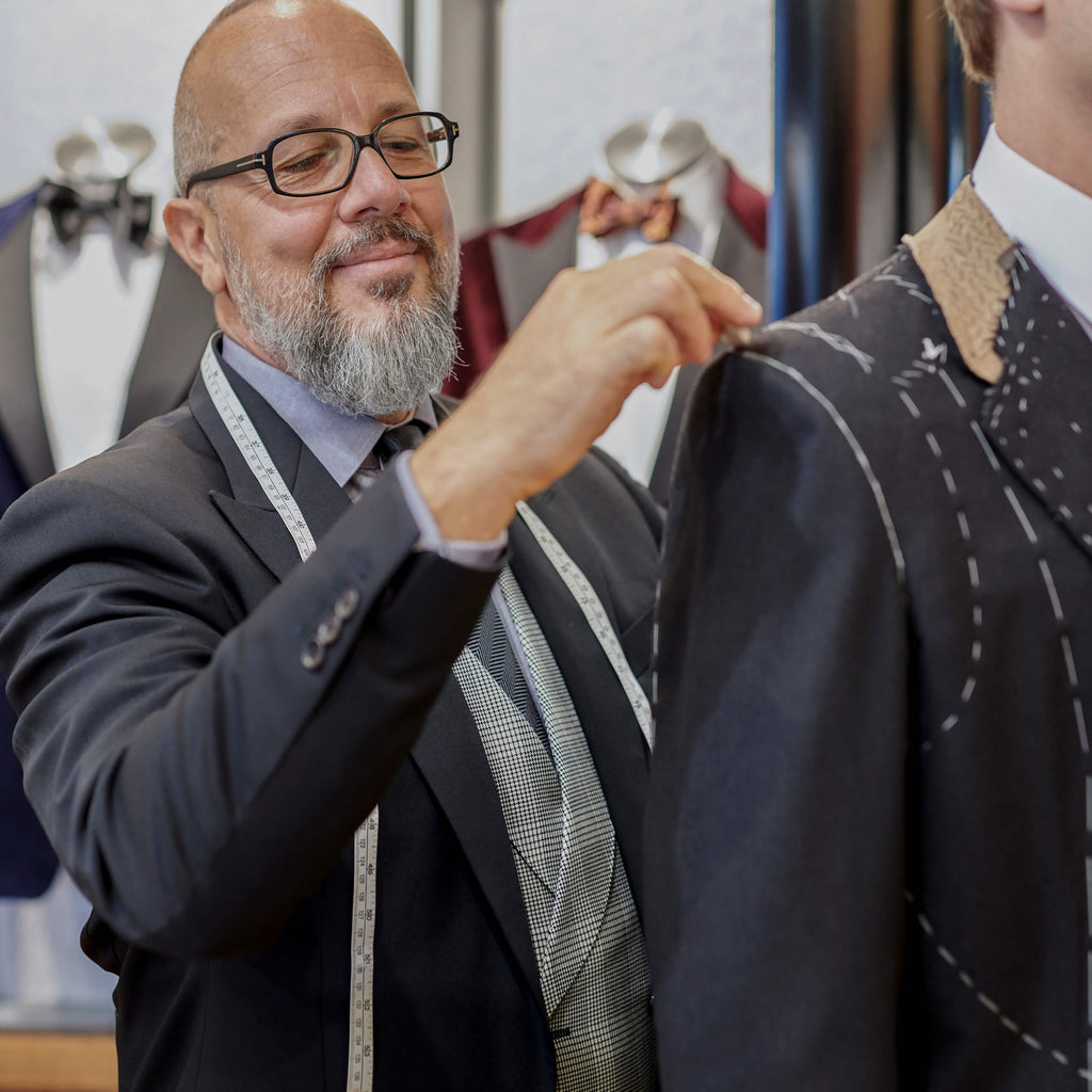 Tailor doing a suit fitting and marking the jacket with tailor's chalk.