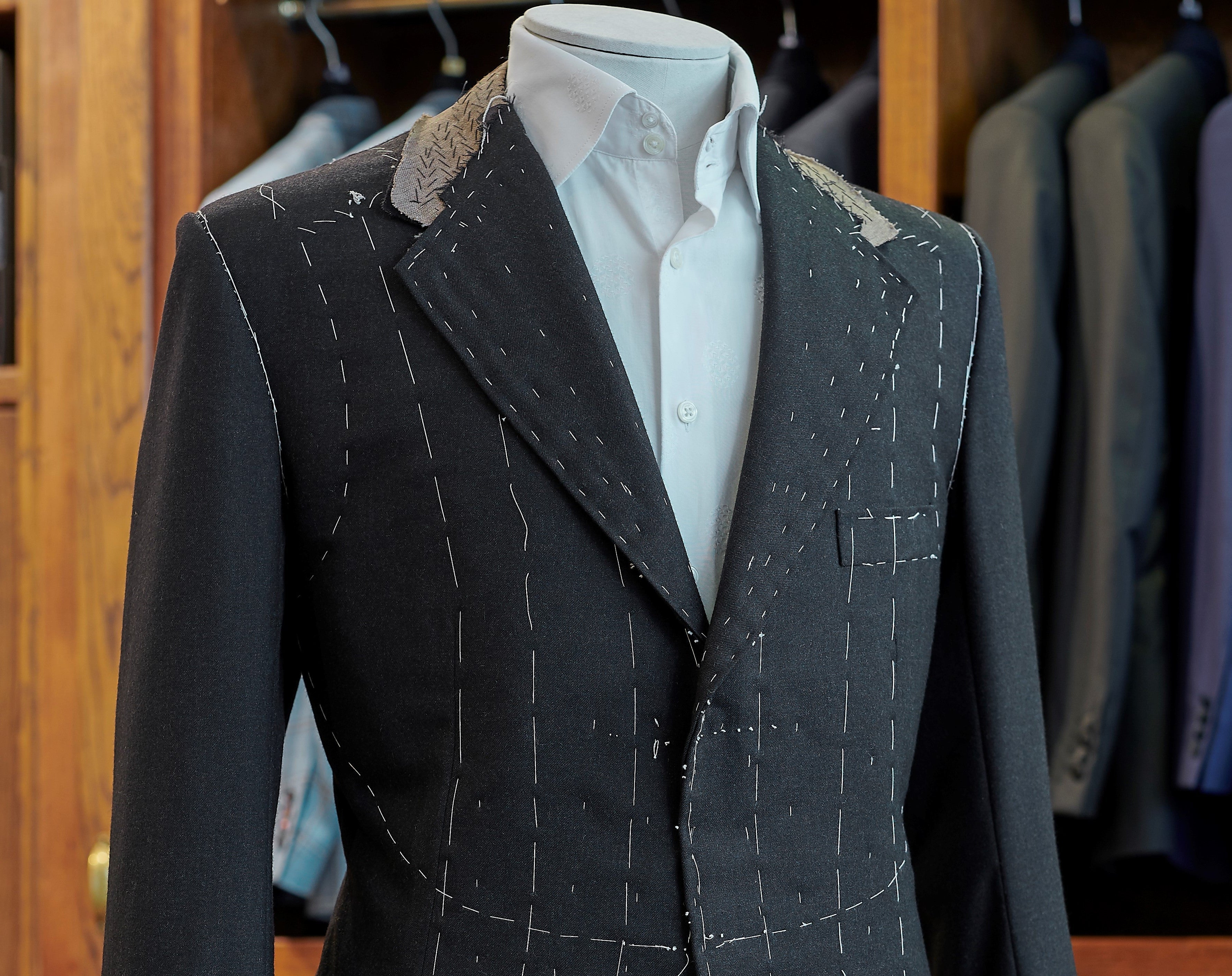 Charcoal suit jacket on a mannequin with a white shirt in a Savile Row store.