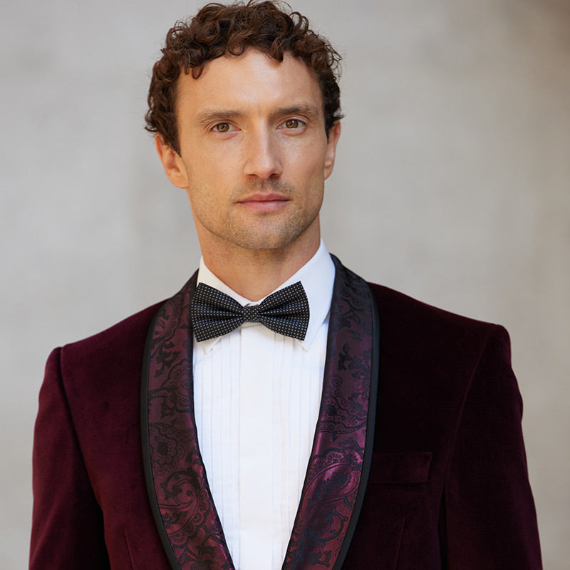 Man wearing a burgundy velvet tuxedo jacket with a bow tie 