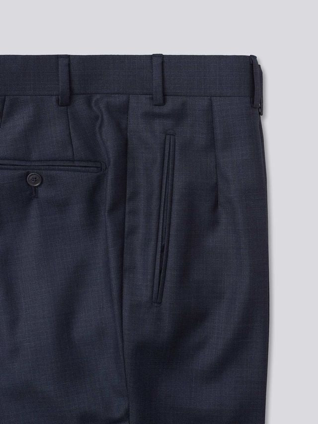 Blue flat-front trousers crafted from Super 130s Italian wool, featuring belt loops, an extension front fastening with a button, and a zip fly. Designed for versatility, they can be finished with either plain bottoms or turn-ups. Additional details include jetted hip pockets, two button-fastening back pockets, grey horn buttons, and a shirt grip inside the waistband for a secure fit.