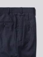 Blue flat-front trousers crafted from Super 130s Italian wool, featuring belt loops, an extension front fastening with a button, and a zip fly. Designed for versatility, they can be finished with either plain bottoms or turn-ups. Additional details include jetted hip pockets, two button-fastening back pockets, grey horn buttons, and a shirt grip inside the waistband for a secure fit.