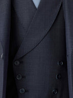A double-breasted blue waistcoat crafted from Super 130s Italian wool, featuring a 3x3 button design with grey horn buttons, welt pockets, and a straight bottom. The navy lining matches the jacket, while the back lining includes a belt and buckle for an adjustable fit.