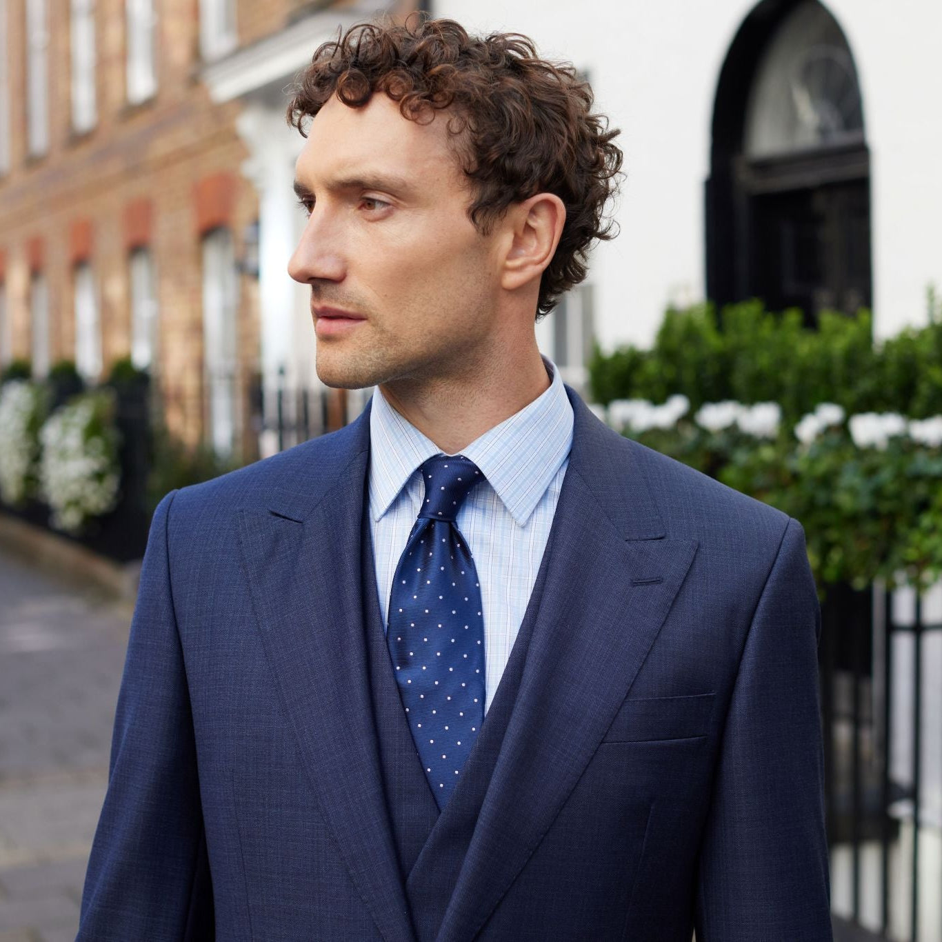 Man in a blue suit and tie standing on Savile Row.