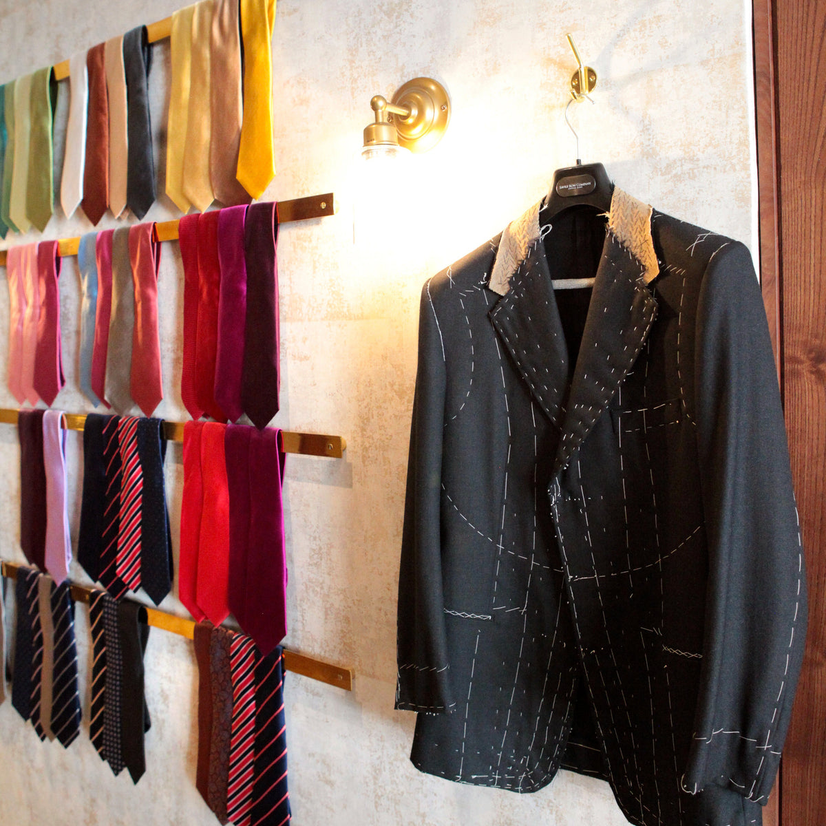 Wall display of ties and a suit jacket in a store setting.