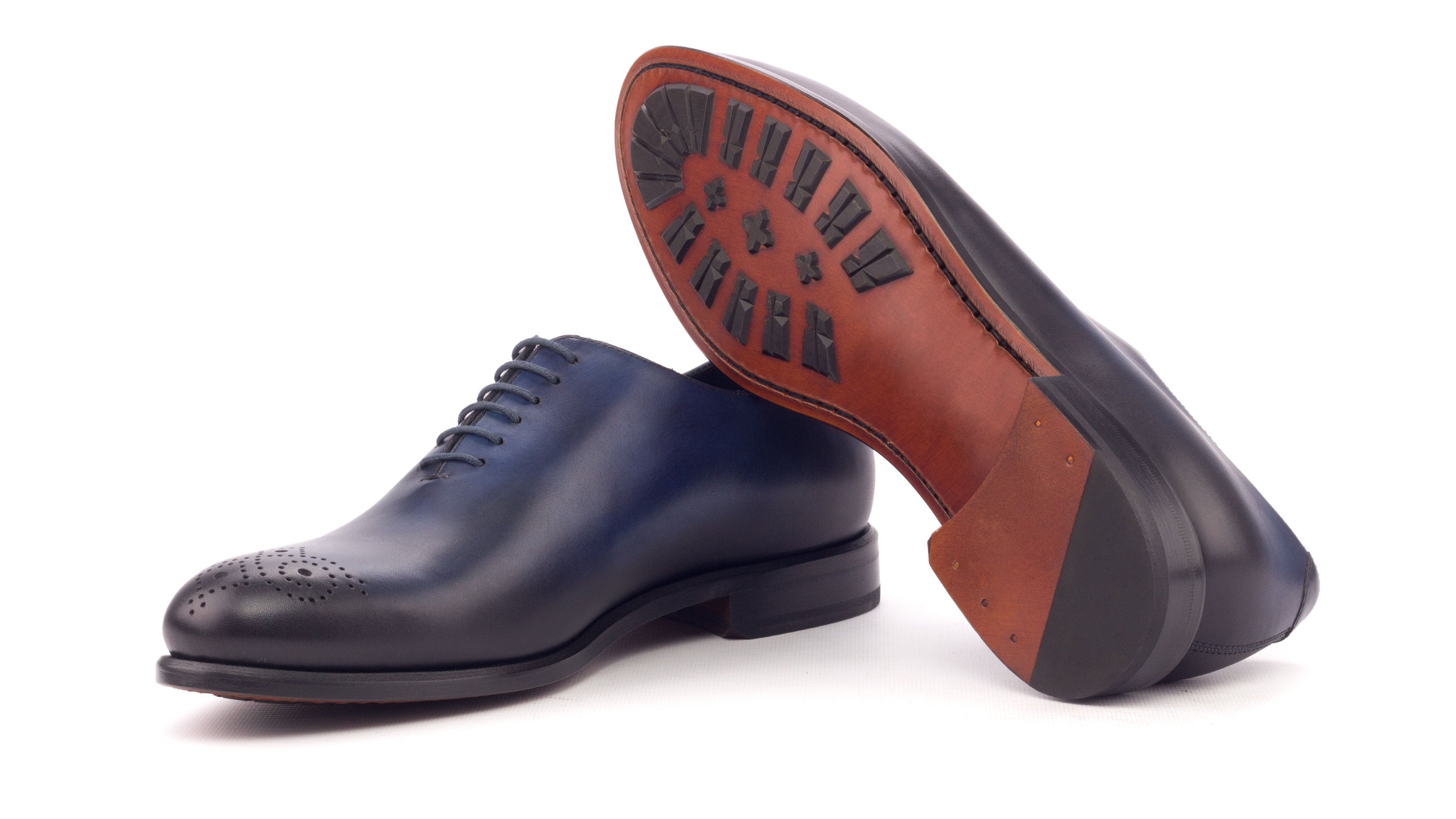Pair of navy and brown sole leather shoes on a white background