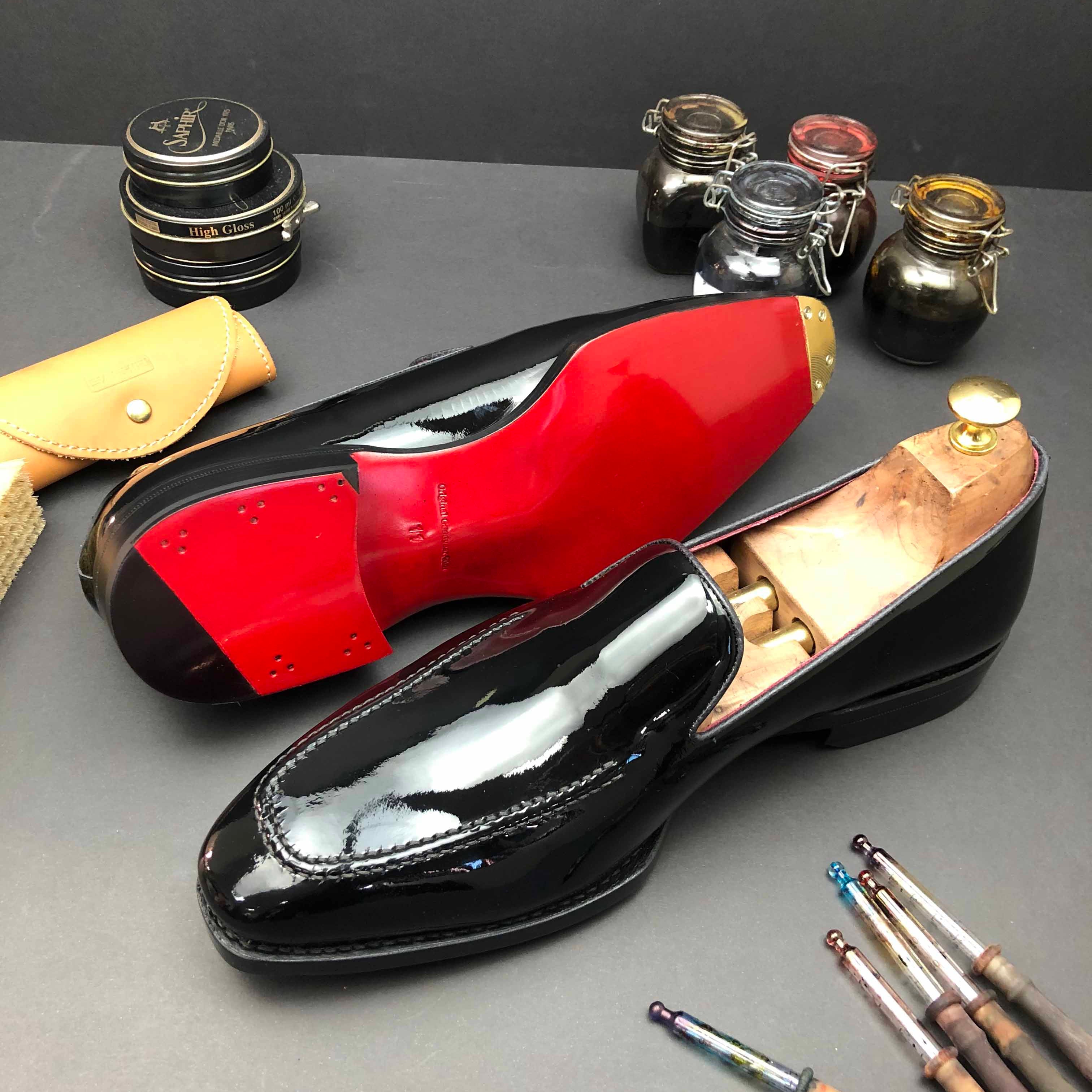 A selection of bespoke shoes and materials used for customisation, including a black shoe with a red sole, along with tools and containers for the crafting process.
