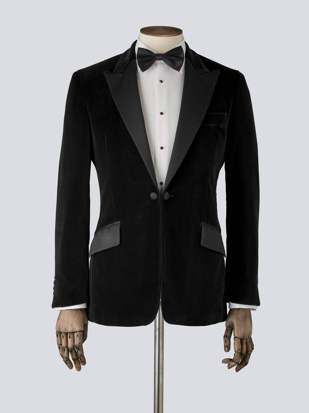 A black velvet dinner jacket designed for black-tie events, featuring a single-breasted one-button closure with a link button, silk peak lapels, and elegant paisley lining. Details include silk-covered buttons, double vents, a handkerchief pocket, and slanted silk pocket flaps that can be tucked in for a jetted look.