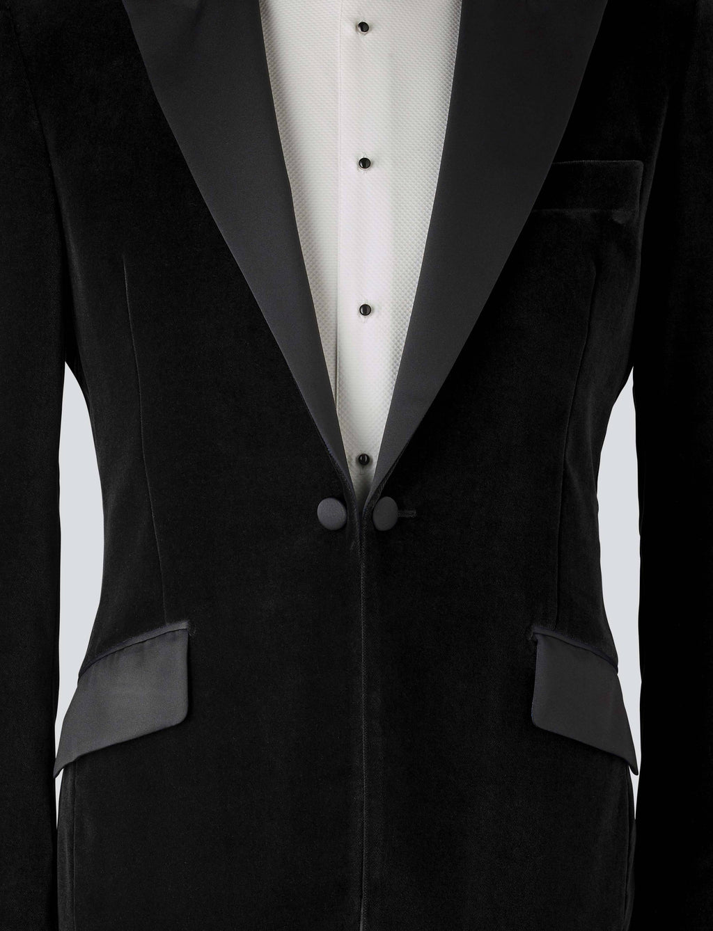 A black velvet dinner jacket designed for black-tie events, featuring a single-breasted one-button closure with a link button, silk peak lapels, and elegant paisley lining. Details include silk-covered buttons, double vents, a handkerchief pocket, and slanted silk pocket flaps that can be tucked in for a jetted look.
