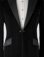 A black velvet dinner jacket designed for black-tie events, featuring a single-breasted one-button closure with a link button, silk peak lapels, and elegant paisley lining. Details include silk-covered buttons, double vents, a handkerchief pocket, and slanted silk pocket flaps that can be tucked in for a jetted look.