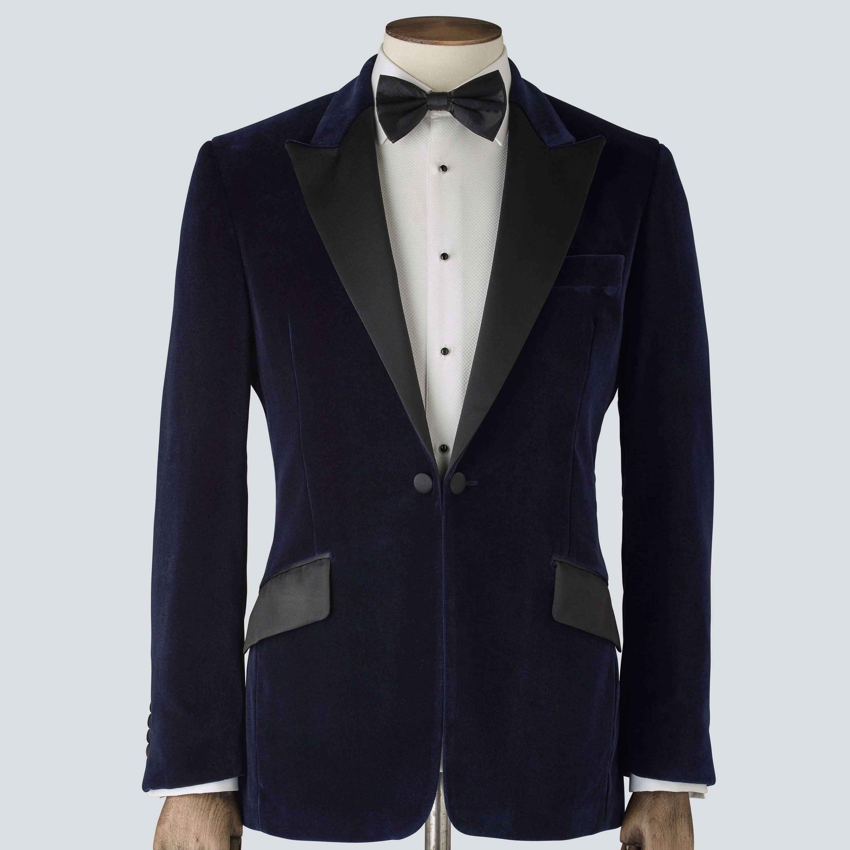 A navy blue velvet tailored dinner jacket with a classic collar, silk peak lapels, and a single-breasted design. 